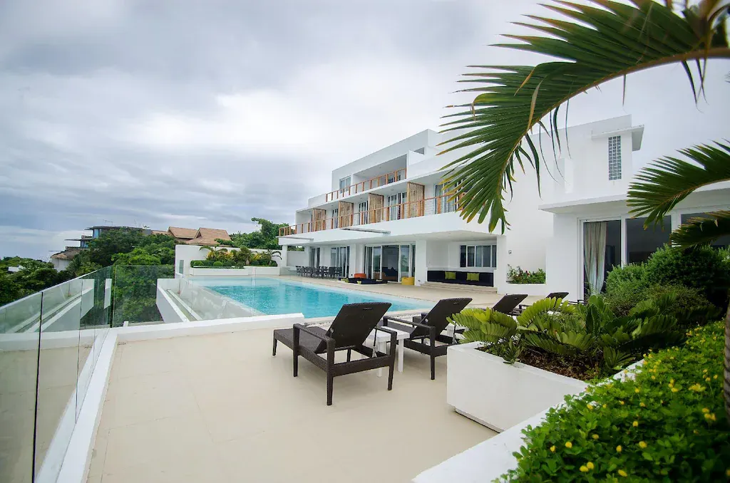 Pool deck with sun loungers and the three-level villa
